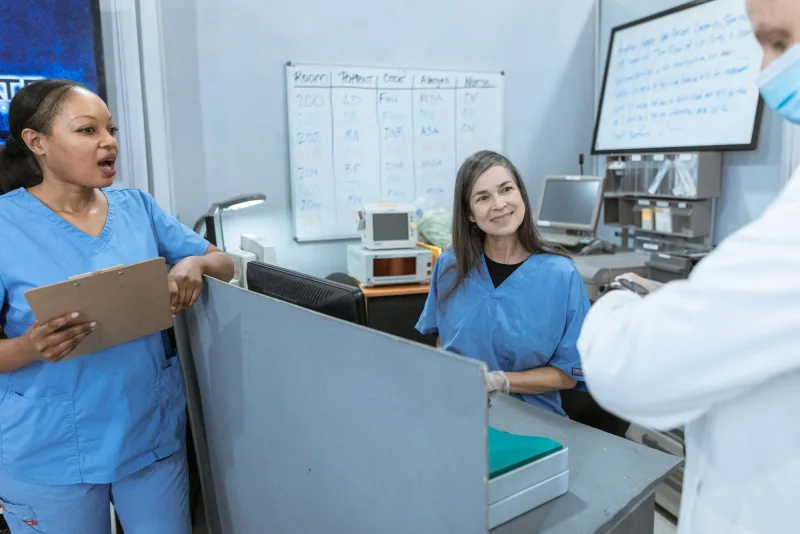 Clinical colleagues discussing their work at a shared workstation.